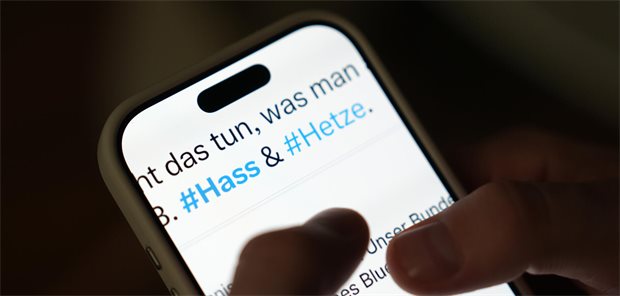 Handy mit den Hastags #Hass und #Hetze auf dem Bildschirm.