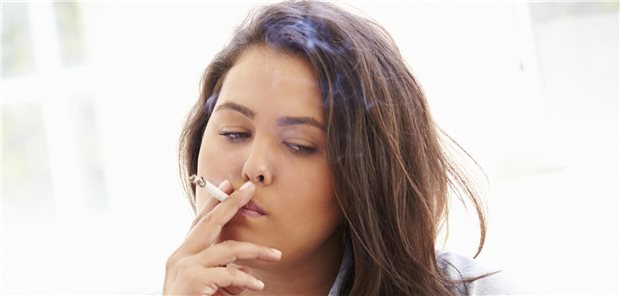 Eine Frau mit dickem Bauch raucht und trinkt