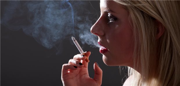 Frau mit Zigarette raucht im Schatten