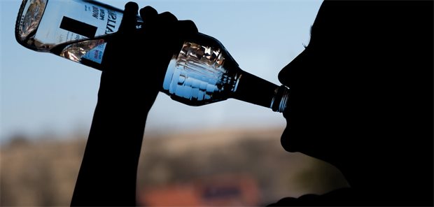 Ein Mädchen trinkt in ihrem Zimmer eine Flasche Wodka. 
