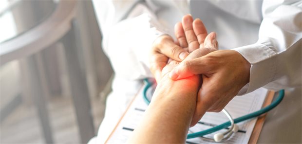 Ein Arzt untersucht die Hand und Finger einer Patientin mit Verdacht auf Rheumatoide Arthritis.