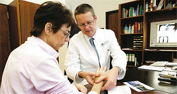 Rheumatologe berät eine Patientin mit Schmerzen in den Handgelenken.