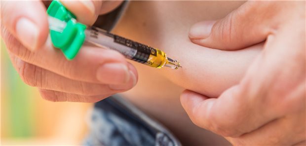Eine Person sticht sich mit einem Insulin-Pen in den Bauch. 