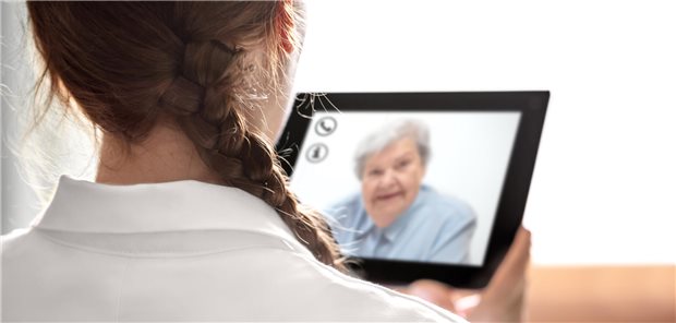 Eine Ärztin von hinten in einer Fernbehandlung per Tablet-PC