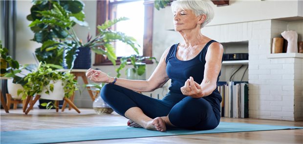 Eine Frau übt Yoga in ihrem Wohnzimmer. 