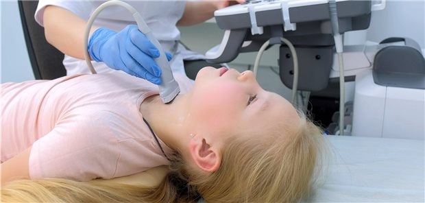Arzt untersucht ein Mädchen an der Schilddrüse mit Ultraschall-Scanner.