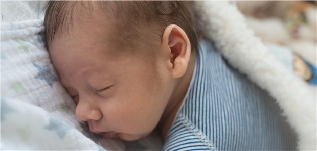 Ein Säugling schläft in Bauchlage.