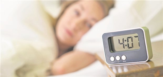 Frau schaut zum Wecker, der auf 4:01 steht.