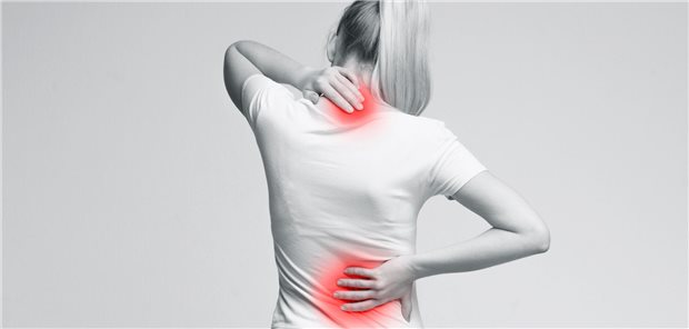 Eine Frau hält sich den schmerzenden Rücken und Nacken fest.