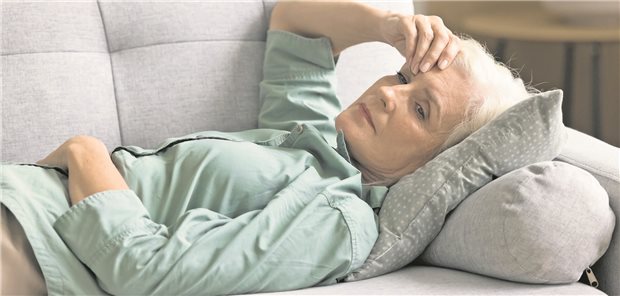 Eine Frau liegt erschöpft auf einem Sofa. 
