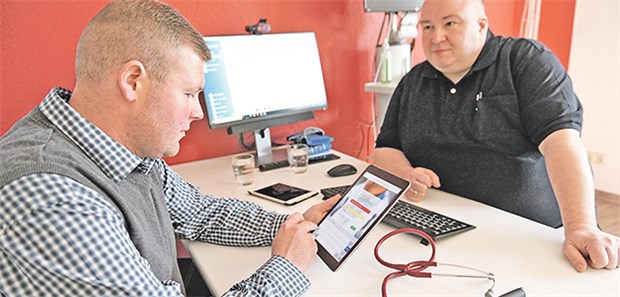 Blaupause für vernetzte Versorgung Schnellerer Datentransfer: Patient Anthony Jyß (links) lässt sich von seinem Hausarzt Dr. Christian Bauer die E-Akte erklären.