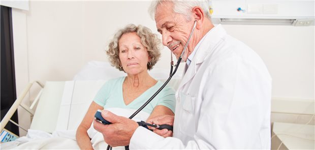 Älterer Arzt macht eine Blutdruckmessung im Heim oder im Krankenhaus.
