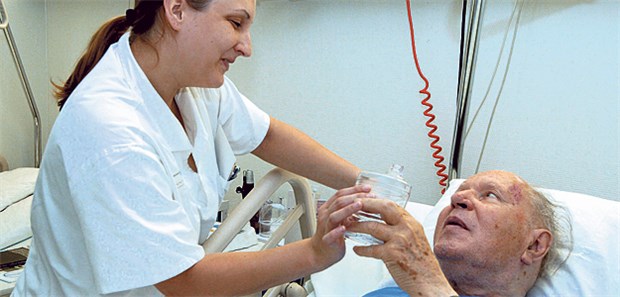 Es knirscht bei der Pflege Schwester unterstützt einen Patienten. Die Personalschlüssel auf Station treiben die Bund-Länder-Arbeitsgruppe zur Klinikreform um.