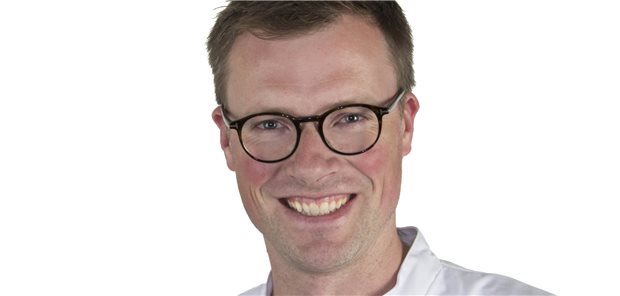 Lächelnder Herr jüngeren Alters mit schwarzer Brille – ein Portraitfoto Sebastian Ottes.