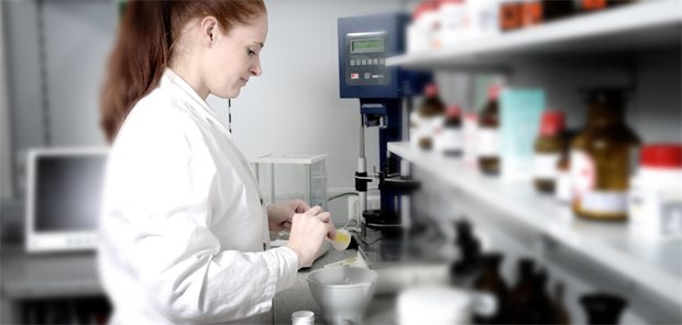 Frau in weißem Kittel steht in einem Apothekenlabor