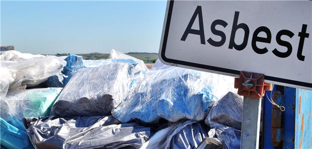 Vor einem Container ist ein Schild mit der Aufschrift "Asbest". 