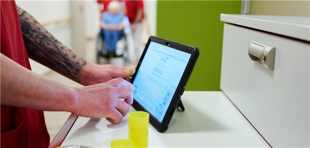 Eine Pflegekraft dokumentiert ihre Arbeit auf einem Tablet-Computer.