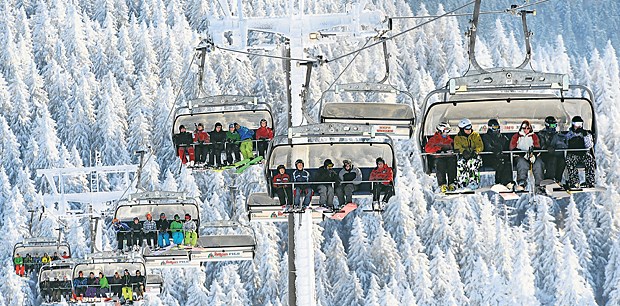 Chirurgie-Praxis direkt neben der Piste Sie warten schon auf die nächste Abfahrt: Ski- und Snowboardfahrer sitzen auf dem Feldberg im Schwarzwald in den Gondeln eines Skilifts.