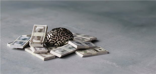 Gehirn aus Metall liegt auf vielen Geldscheinen