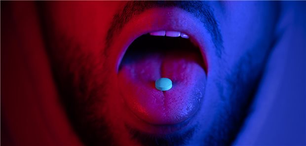 Mann mit Tablette auf der Zunge