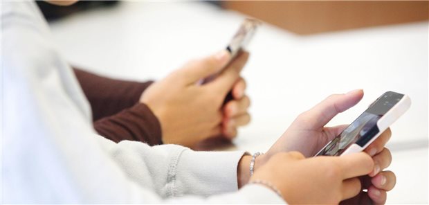Zwei Kinder halten im Unterricht ihre Smartphones in der Hand