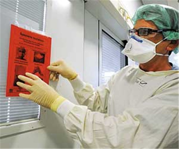 "Da fühlt man sich erst einmal wie ausgestoßen" Spezielle Isolation: Ein Arzt befestigt ein Hinweisschild an einem Krankenzimmer der Intensivstation.