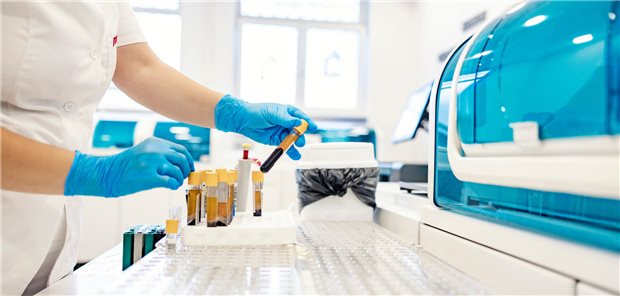 Eine Mikrobiologin entnimmt ein Reagenzglas mit einer Blutprobe für DNA- und wissenschaftliche Tests.