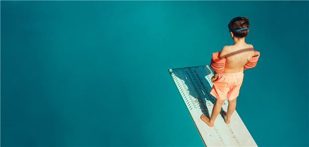 Kind auf Springbrett über Wasser.