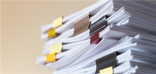 Ein Stapel mit durch Büroklammer zusammen gehaltenen Dokumenten.