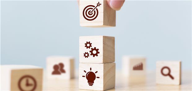 bedruckte Bauklötzchen werden aufeinander gestapelt (Symbolbild für Bewältigung des SARS-CoV-2-Pandemiealltags).