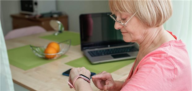 Ältere Frau, die ihre Gesundheitsdaten (Puls, Temperatur, Blutdruck, Schritte und Schlaf) mit einer intelligenten Uhr überprüft.
