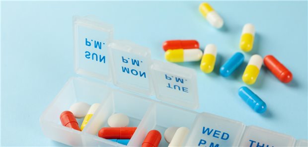 Plastikbehälter mit Tabletten auf blauem Hintergrund.