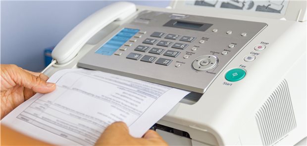 Jemand nimmt ein Fax aus dem Gerät entgegen.