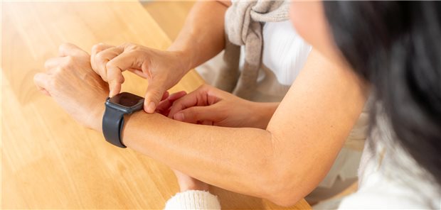 Hypertonie: Wenn die Smartwatch in falsche Sicherheit wiegt Die erwachsene Tochter zeigt ihrer älteren Mutter, wie man Healthtech-Geräte wie eine Smartwatch mit mobiler App nutzt, um zu Hause Gesundheit, Herzfrequenz und Blutdruck zu überwachen.