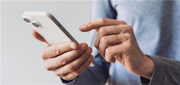Ein Mann tippt etwas in ein Smartphone.