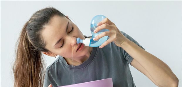 Ein junge Frau benutzt eine Nasendusche zur großvolumige Spülungen mit lokal wirksamen Antibiotika zur Behandlung von chronischer Rhinosinusitis.
