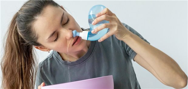 Ein junge Frau benutzt eine Nasendusche zur großvolumige Spülungen mit lokal wirksamen Antibiotika zur Behandlung von chronischer Rhinosinusitis.