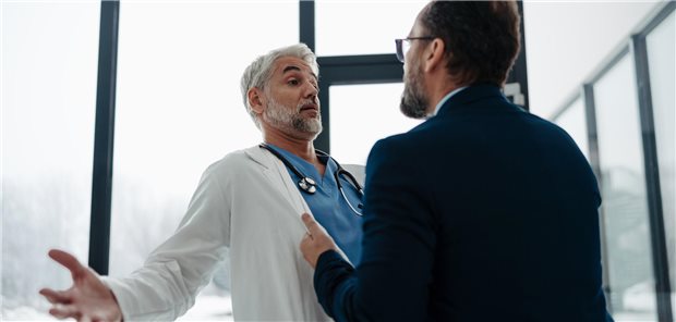 Ein Patient packt einen Arzt am Kittel.
