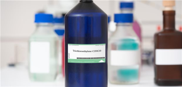 Eien Glasflasche steht in einem Labor, dahinter stehen weitere Glasflaschen.