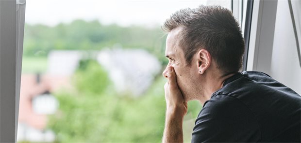 Mann sitzt am Fenster und starrt hinaus