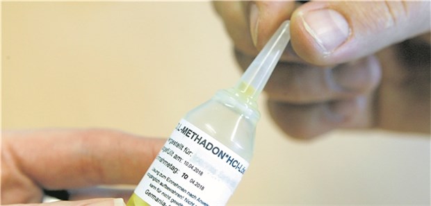 Übergabe eines Behälters mit Methadon an einen drogensüchtigen Patienten.