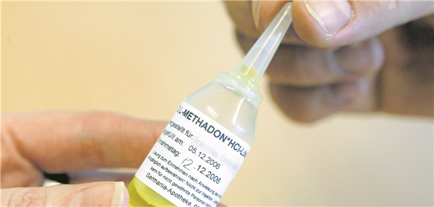 Übergabe eines Behälters mit Methadon an einen drogensüchtigen Patienten.
