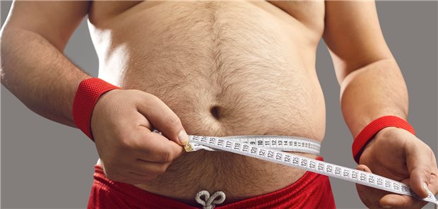 Mann mit Maßband um den nackten Bauch.