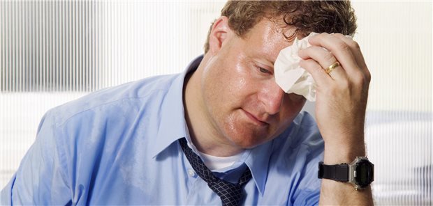 Ein Mann mit naßgeschwitztem Gesicht und Hemd tupft sich mit einem Tuch die Stirn ab.