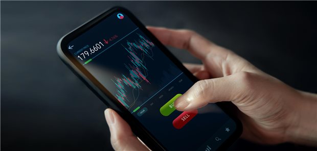 Nahaufnahme einer Person, die über eine Online-Handelsplattform mit ihrem Mobiltelefon etwas kauft.