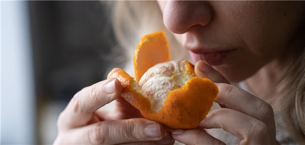 Eine Frau versucht, den Geruch frischer Mandarinen wahrzunehmen, um die Einschränkung ihres Geruchssinns zu bewerten.