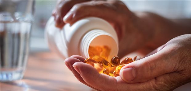 Vitamin D-Pillen in der Hand eines Menschen.