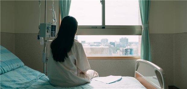 Junge Frau schaut aus einem Krankenhausfenster