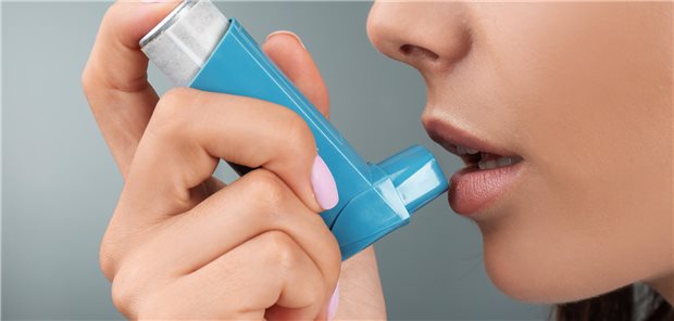 Nahaufnahme der Mund- und Nasenpartie einer junge Frau, die einen Asthma-Inhalator benutzt.