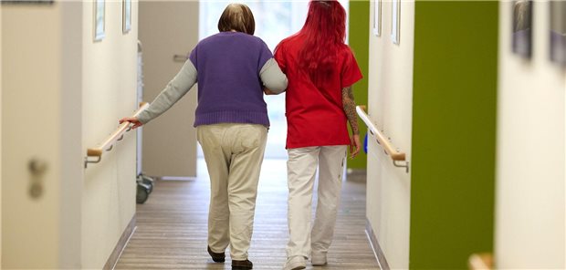 Eine Pflegekraft begleitet im DRK-Pflegezentrum Solferino eine Seniorin durch den Flur.